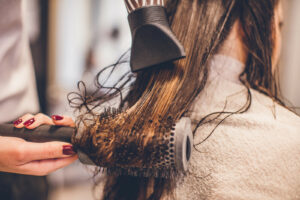 Woman drying hair with a hair dryer and brush